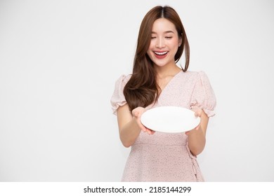 Young Asian woman holding and looking at empty white plate or dish isolated on white background