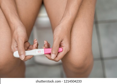 Young asian woman holding pregnancy test showing a positive result in bathroom, Wellness and healthy concept, Abortion problem, Selective focus.