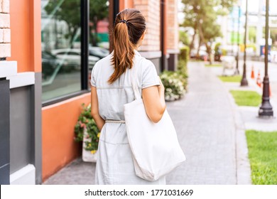 Young asian woman holding a reusable bag and walking in the city, Zero waste concept - Powered by Shutterstock