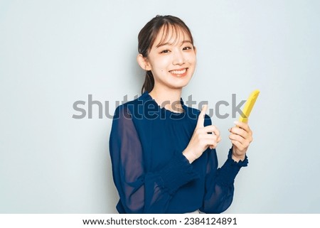 A young Asian woman holding a smartphone and smiling.