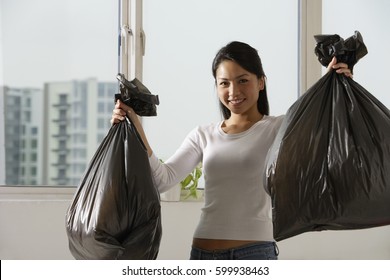 Young Asian Woman Holding Up Trash Bags