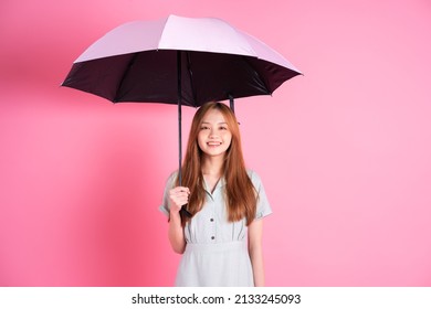 Young Asian Woman Holding Umbrella On Pink Background