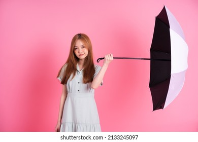 Young Asian Woman Holding Umbrella On Pink Background