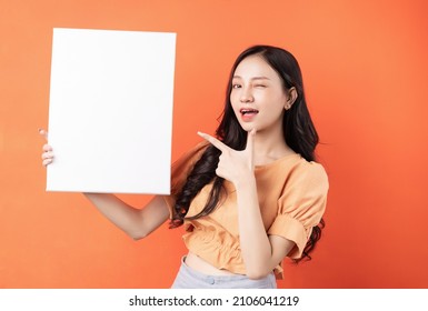 Young Asian Woman Holding White Board On Orange Background	