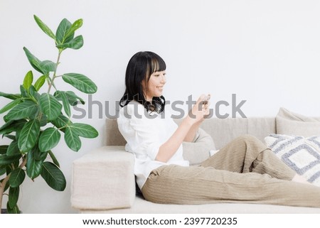Young Asian woman at home watching drama with her phone