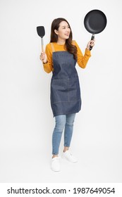 Young Asian woman housewife wearing kitchen apron cooking and holding pan and spatula isolated on white background, Full body composition