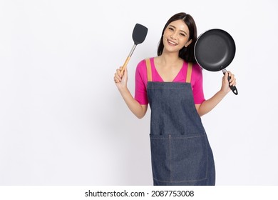 Young Asian woman housewife wearing kitchen apron cooking and holding pan and spatula isolated on white background - Powered by Shutterstock