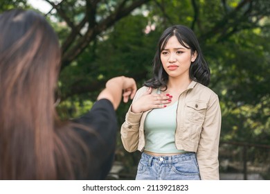 A young asian woman is hurt and confused about the accusations hurled on her by another girl. A falling-out between friends. Outdoor scene.