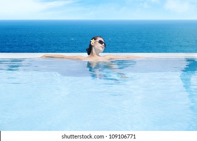 Young Asian Woman In The Infinity Pool Enjoying The Ocean View