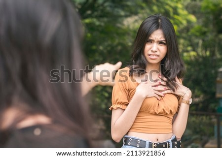 A young asian woman is insulted by accusations hurled on her by another girl. Standoff at a park.