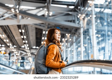 Young asian woman in international airport terminal or modern train station. Backpacker passenger female commuter walking on escalator - Powered by Shutterstock