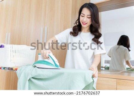 Young Asian woman ironing clothes
