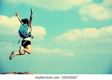 Young Asian Woman Jumping On Mountain Peak Cliff