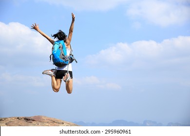 Young Asian Woman Jumping On Mountain Peak Cliff