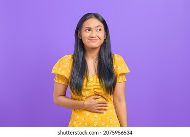 Young Asian Woman Keep Hands On Stomach And Feel Satiety After Eating Tasty On Purple Background