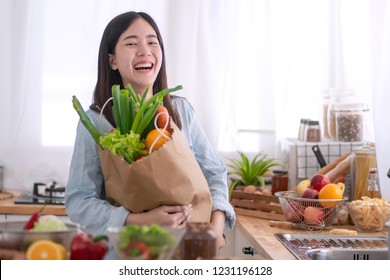 Young Asian Woman In The Kitchen And Holding Grocery Shopping Bag
