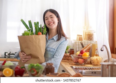 Young Asian Woman In The Kitchen And Holding Grocery Shopping Bag 