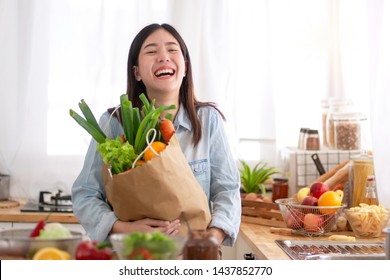 Young Asian Woman In The Kitchen And Holding Grocery Shopping Bag 