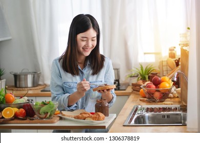 Young Asian Woman In The Kitchen Prepare And Eating Sandwich For Breakfast