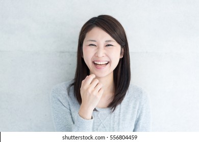 Young Asian Woman Laughing Against Concrete Wall