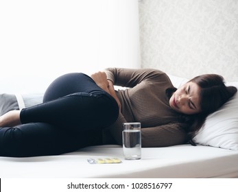 Young Asian Woman Laying Down On Bed,she's Stomach Pain In Her Bedroom.