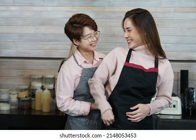 young asian woman LGBTQ lesbian couple working and teasing each other in business owner coffee shop. concept for LGBTQ lifestyle, cohabitation, relationship etc                              