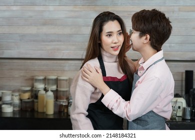 young asian woman LGBTQ lesbian couple romantic whisper while working in business owner coffee shop. concept for LGBTQ lifestyle, cohabitation, relationship etc    