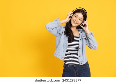 Young Asian woman listening favourite music on mobile phone application with wireless headphones and dancing isolated on yellow background - Powered by Shutterstock