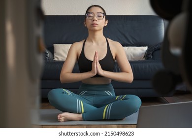Young asian woman listening relaxing music and meditating doing the easy pose (Sukhasana) at home.