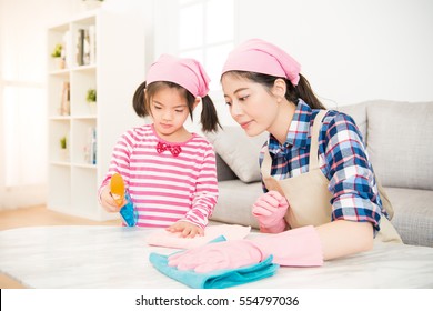 Young Asian Woman And A Little Child Girl Wiped The Dusting Table In The Living Room At Home. Mother And Daughter Do The Cleaning In The House. Family Housework And Household Concept.