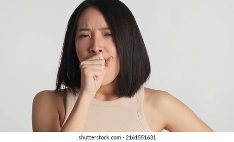 Young Asian Woman Looking Bored Over White Background. Not Interested Expression. Female Yawning Covering Mouth With Palm Isolated