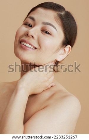 young asian woman looking in camera on beige background.