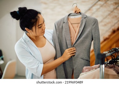 Young Asian Woman Looking At Her Clothes While Choosing What To Wear And Getting Ready For Work.