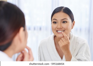 Young Asian Woman Looking At Her Teeth In The Mirror