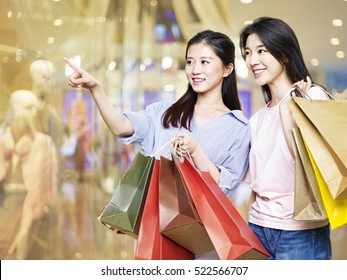 Young Asian Woman Looking Into Shop Windows In Shopping Mall