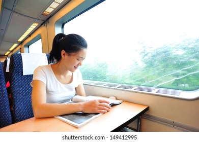 Young Asian Woman Looking Magazine Interior Of Train/subway 