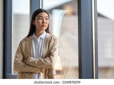 Young asian woman looking outside window with uncertainty while thinking about her future business. - Powered by Shutterstock