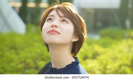 Young Asian Woman Looking Up To Sky.