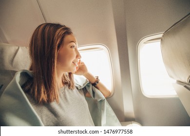 Young Asian Woman Looking At The Window In Air Plane, Travel And Transport Concept