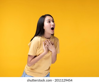 Young Asian woman making hand gesture with surprise face. Happy Asian woman wearing yellow t-shirt standing over yellow background. Portrait of happy Asian female.