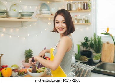 Young Asian Woman Making Salad In Kitchen Smiling And Laughing Happy At Home.