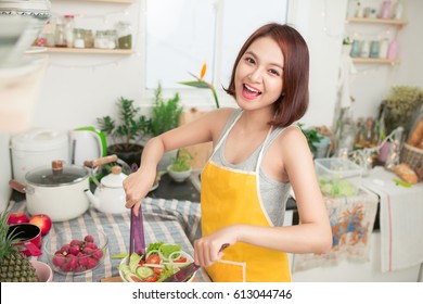 Young Asian Woman Making Salad In Kitchen Smiling And Laughing Happy At Home.