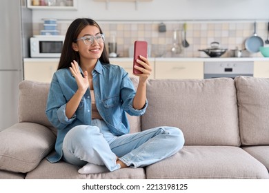 Young asian woman making video calling with smartphone using conferencing meeting online app at home. Happy teen girl waving to friend on phone screen. Remote communication videocall concept - Powered by Shutterstock