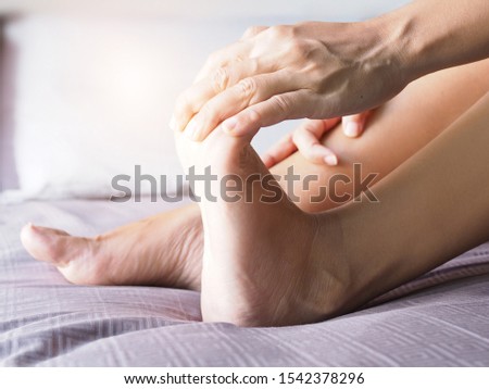 Young asian woman massaging on barefoot to relax muscle of foot pain, soles, heels and toe from foot diseases.