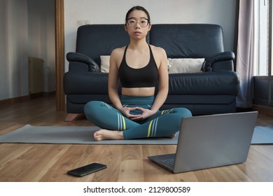 Young asian woman meditating doing the easy pose (Sukhasana) at home.