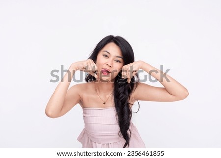 A young asian woman mocking someone, sticking her tongue out while making a sarcastic crying gesture. Isolated on a white background.