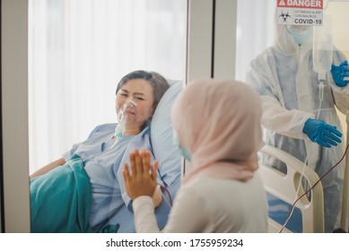 Young Asian Woman Muslim Meet Family Mother Is Elderly Patient Behind Glass Window Of Negative Pressure Room At Hospital Which Sad And Felling Care, Miss And Love. Pandemic Of Corona Virus, COVID19.