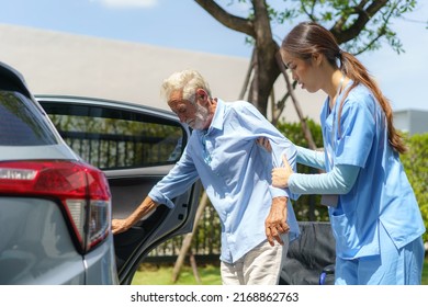 Young Asian woman nurse care giver helping handicapped elderly into car in fornt of home.
