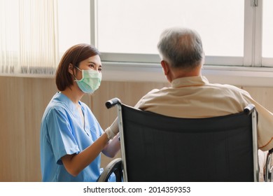 Young Asian woman nurse explaining information to elderly man patient in wheelchair with friendly smiley face in the hospital. Young Assistance with old people in the elderly care place.