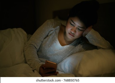 Young asian woman on bed late at night texting using mobile phone sleepy and tired in internet communication overuse and smartphone addiction. Wife using smartphone waiting husband with boring emotion - Shutterstock ID 768850765